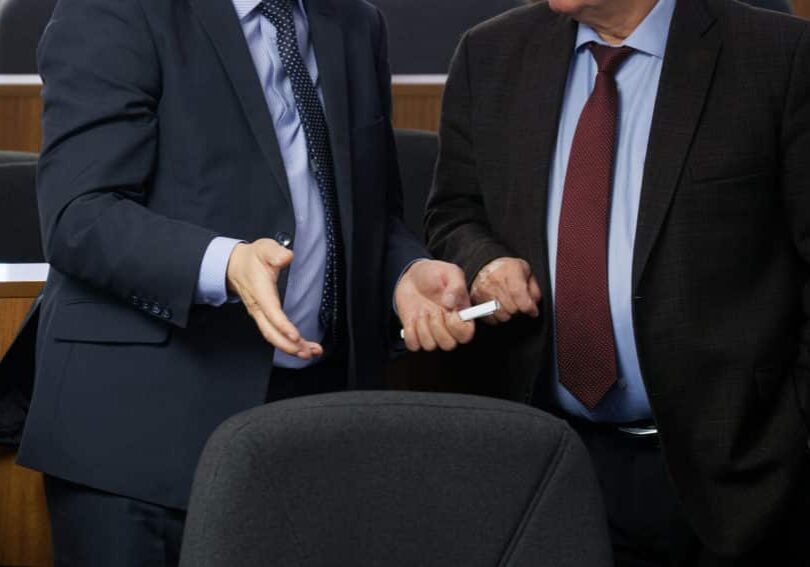 Two politicians or businessmen are talking to each other before the start of a meeting or conference. Discussion of the pressing issues of our time. Preparing for a decision. Without a face.