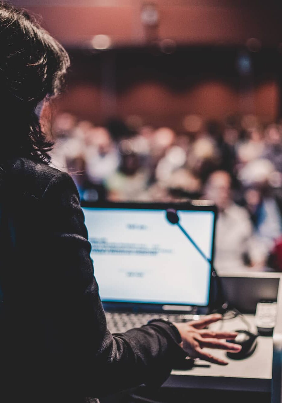 Female speaker giving a talk on corporate business conference. Unrecognizable people in audience at conference hall. Business and Entrepreneurship event.