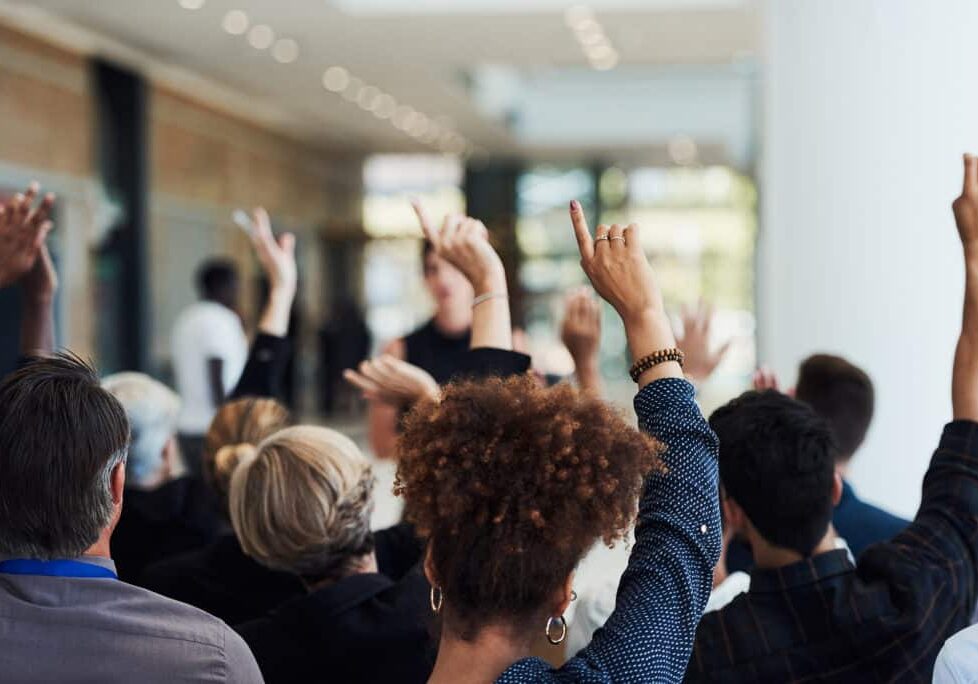 Shot of a group of businesspeople raising their hands to ask questions during a conference