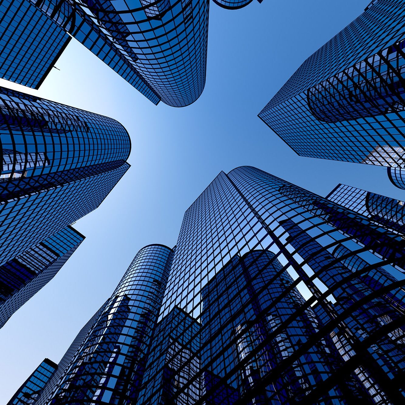 Low angle shot of modern glass city buildings with clear sky background.